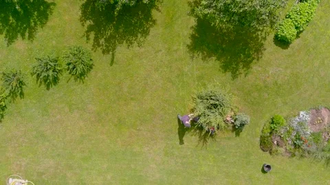 Aerial top-down view of a man mowing grass with petrol lawn mower in a backyard. Stock Footage 278803019