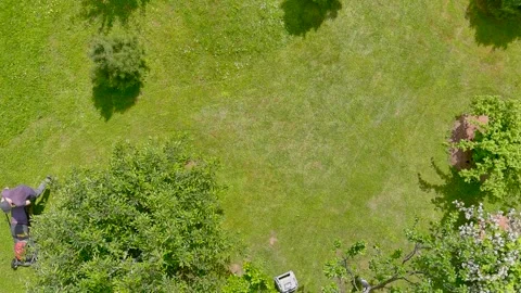 Aerial top-down view of a man mowing grass with petrol lawn mower in a backyard. 스톡 동영상 312016771
