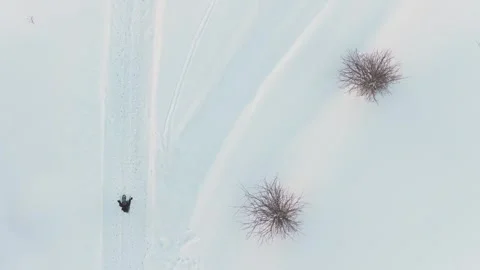 Aerial top down view man hiking with snowshoes through deep snow in winter .. Stock Footage 342378449