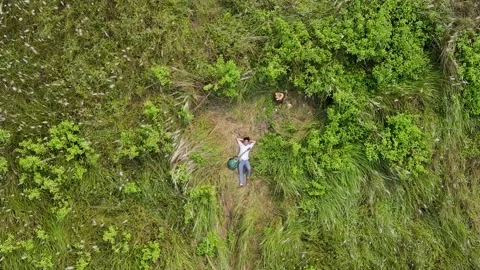 Aerial top down view of man relaxing in green meadow Stock Footage 346677366