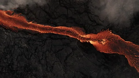Aerial Top-Down View of Molten Lava River Flowing Through Volcanic Basalt Field Stock Footage 325503935