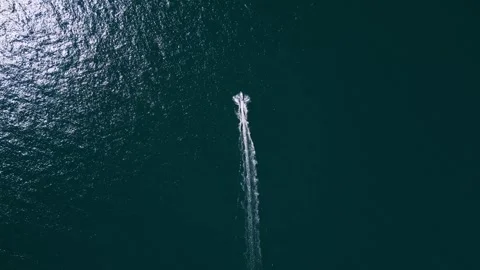 Aerial top down view of a motorboat speeding across deep blue ocean water Stock Footage 346232363