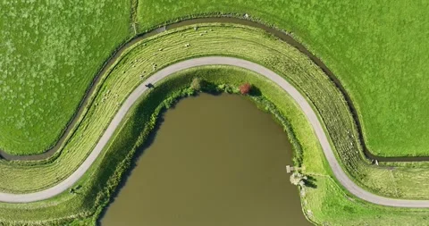 Aerial top down view of a motorcycle driving on a winding dam road. Stock Footage 327797453