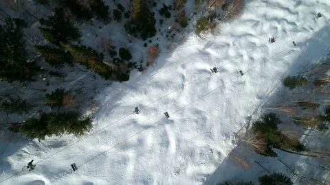 Aerial top down view on a moving chair lift between the trees at ski resort Stock-Footage 153727285
