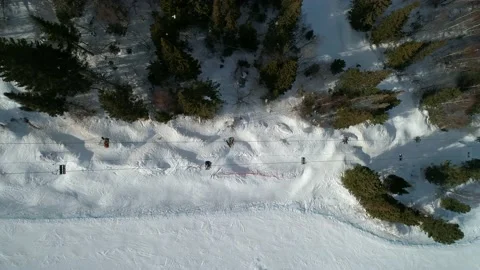 Aerial top down view on a moving chair lift between the trees at ski resort Stock Footage 153727318