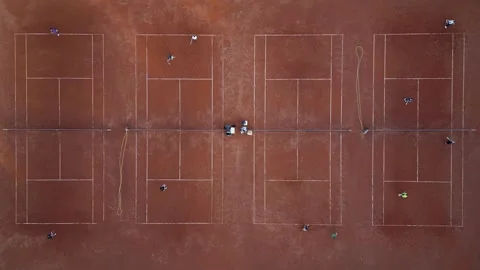 Aerial top-down view of multiple red clay tennis courts with players practicing Video stock 310183375