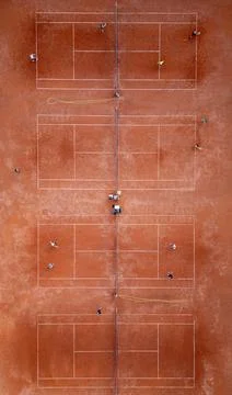 Aerial top-down view of multiple red clay tennis courts with players practicing Stock Photos