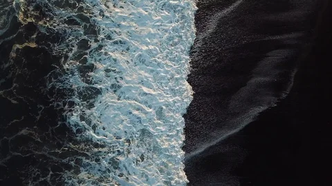 Aerial top down view of ocean wave on black sand beach in Iceland Stock Footage 108940190