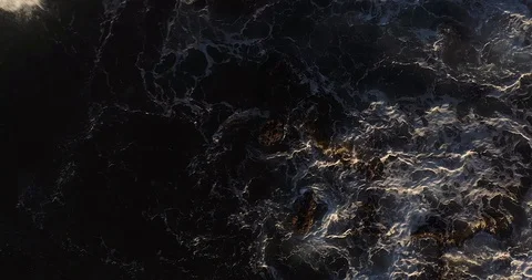 Aerial top down view of ocean waves splashing on shoreline rocks Stock Footage 124752822