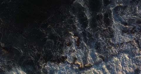 Aerial top down view of ocean waves splashing on shoreline rocks Stock Footage 124752905