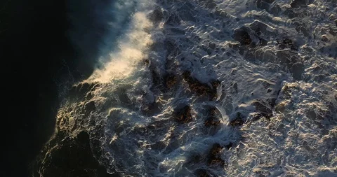 Aerial top down view of ocean waves splashing on shoreline rocks Stock Footage 124752970