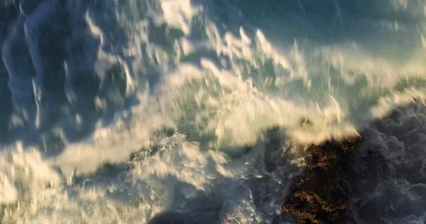 Aerial top down view of ocean waves splashing on shoreline rocks Stock Footage 124753295