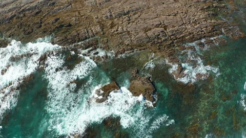 Aerial top down view of ocean waves crashing on rocky shore Video stock 170734916