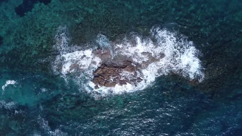 Aerial top-down view of ocean waves crashing against a rocky reef Video stock 302002240