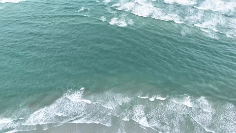 Aerial top down view of ocean waves crashing on a sandy beach Stock Footage 323915786