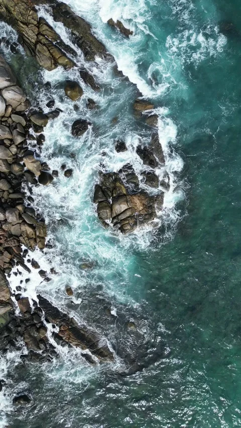 Aerial Top Down View of Ocean Waves Crashing on Rocky Coastline in Phuket, Stock Footage 335583451
