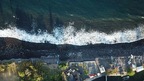 Aerial Top Down View of Ocean Waves Crashing on Black Rocky Beach Stock Photos