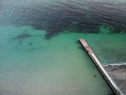Aerial top down view of old concrete pier or breakwater with emerald sea water Stock-Fotos