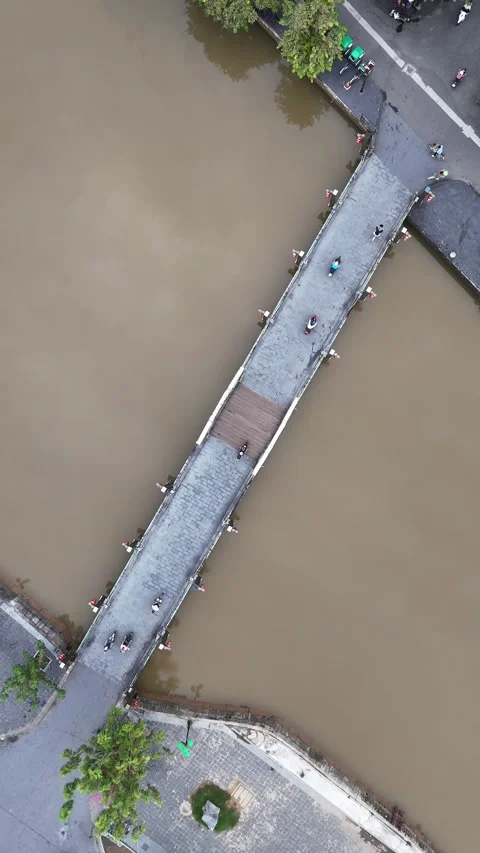 Aerial Top Down View of Pedestrian Bridge Traffic Over Muddy River in Hoi An, Stock Footage 335832131