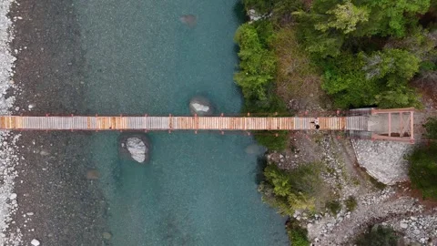 Aerial top down view of people on a wooden suspension bridge crossing a river Stockbeeldmateriaal 334801974