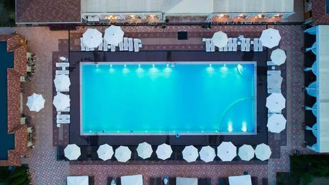 Aerial top down view of rectangular swimming pool with umbrellas and loungers at Stock Photos