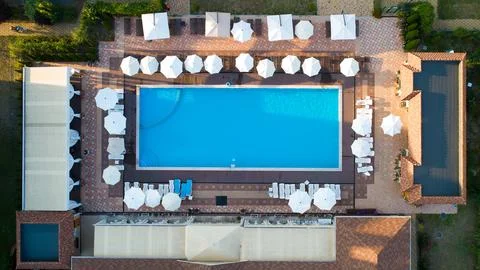 Aerial top down view of rectangular swimming pool with umbrellas and loungers at Stock Photos