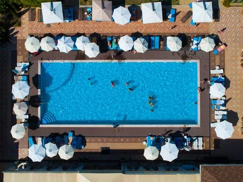 Aerial top down view of rectangular swimming pool with umbrellas and loungers at Stock Photos