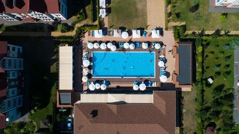 Aerial top down view of rectangular swimming pool with umbrellas and loungers at Stock Photos