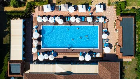 Aerial top down view of rectangular swimming pool with umbrellas and loungers at Stock Photos