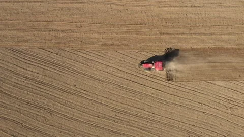 Aerial top-down view of red tractor cultivating dry field in summer Stock Footage 340106081