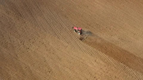 Aerial top-down view of red tractor cultivating dry field in summer Stock Footage 340106092