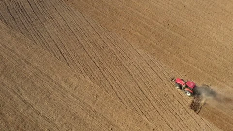 Aerial top-down view of red tractor cultivating dry field in summer Stock Footage 340106122