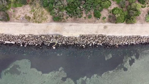 Aerial top down view of a rock wall breakwater and pathway Video stock 342326617