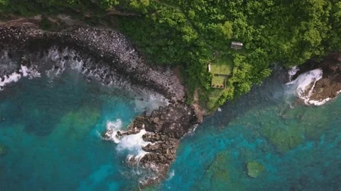 Aerial top down view of rocky coastline with green cliffside and blue sea. Video stock 137445041
