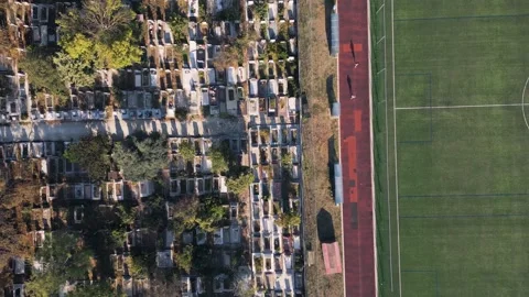 Aerial top down view of running track near cemetery representing life and death Stock Footage 346233337