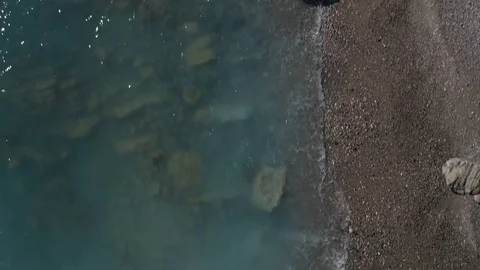 Aerial top down view of a sandy beach with rocks on the Mediterranean sea Stock Footage 125468997