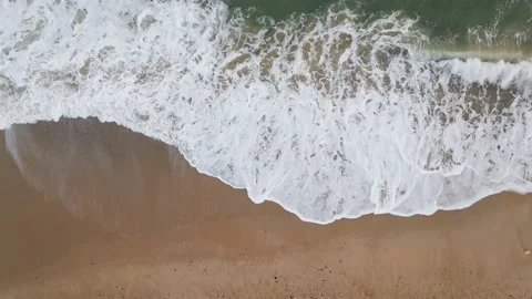Aerial top down view on a sandy beach with sea surf slow motion Video stock 225868986