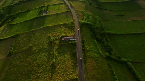 Aerial top-down view of a scenic road winding through lush green pastures on 库存影片 335726502