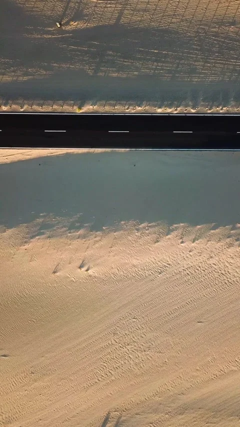 Aerial top-down view showing a solitary car traveling along an empty asphalt Stock Footage 344815830
