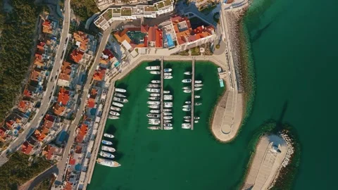 Aerial top down view shows Montenegro marina with yachts at finger piers, palm Stock Footage 328456376