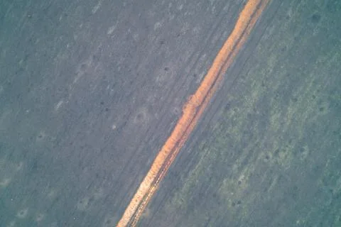 Aerial top down view of single orange military trench line dividing grey field Stock Photos