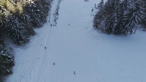 Aerial top down view of a ski lift and skiers descending a snowy slope in winter Stock Footage 336384310