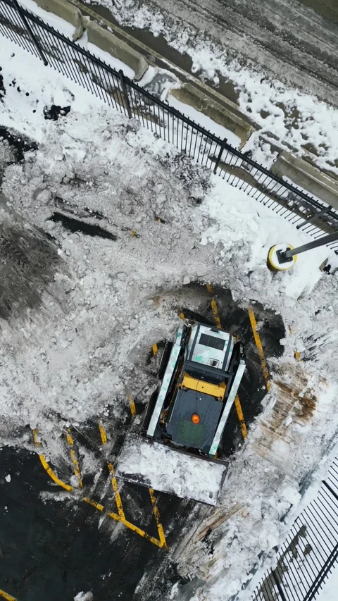 Aerial Top-Down View of Skid-Steer Loader Clearing Snow in Parking Lot Stock-Footage 332504432