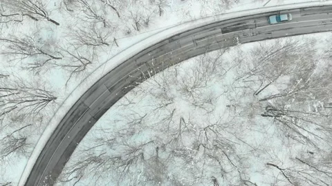 Aerial top-down view of snow covered pine forest and a road winding among trees 스톡 동영상 224401072