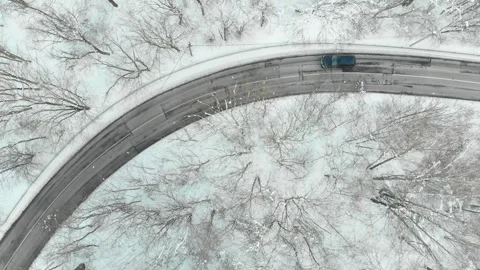 Aerial top-down view of snow covered pine forest and a road winding among trees Video stock 253961351