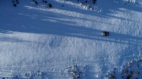 Aerial top down view of a snowcat or snow groomer on a ski resort slope in Stock Footage 102912574
