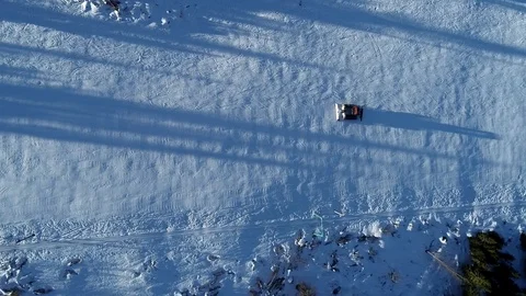 Aerial top down view of a snowcat or snow groomer on a ski resort slope in Stock Footage 102912602