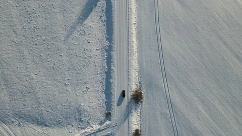 Aerial top down view of the snowy road with black car moving. Shot from drone Stock Footage 197363613