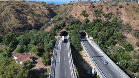 Aerial top-down view of straight highway overpass into twin tunnel Stock Footage 343963153