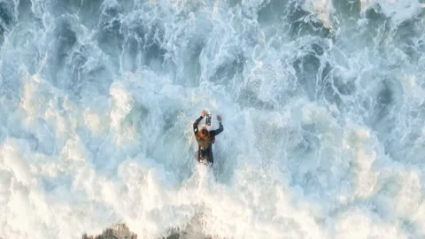 Aerial: Top down view of Surfers battling the waves in the shallows Stock Footage 194899932